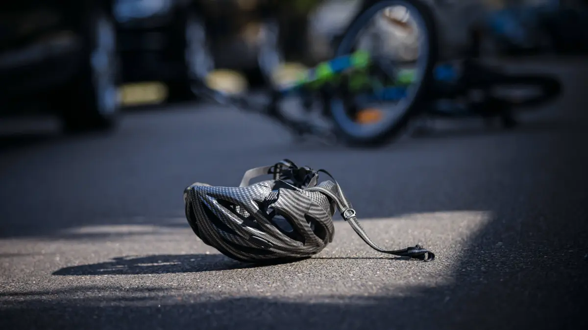 Symbolfoto zum Thema Fahrradunfall gestellte Szene. Ein zerbrochener Fahrradhelm liegt neben einem Fahrrad auf einer Strasse. Berlin, 21.08.2024. Berlin Deutschland *** Symbol photo on the topic Bicycle accident posed scene A broken bicycle helmet lies next to a bicycle on a street Berlin, 21 08 2024 Berlin Germany Copyright: xThomasxTrutschel/photothek.dex
