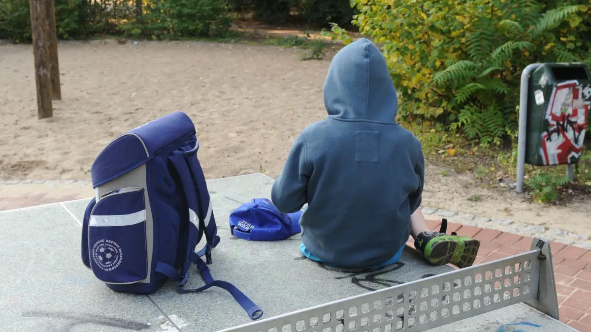 Kind mit Schulranzen auf Spielplatz: ARCHIV - 21.08.2012, Berlin: ILLUSTRATION - Ein Junge sitzt mit seinem Schulranzen auf einer Tischtennisplatte auf einem Spielplatz in Berlin. (zu dpa: «Mehr Verfahren gegen Schulschwänzer in Sachsen») Foto: Jens Kalaene/dpa-Zentralbild/dpa +++ dpa-Bildfunk +++