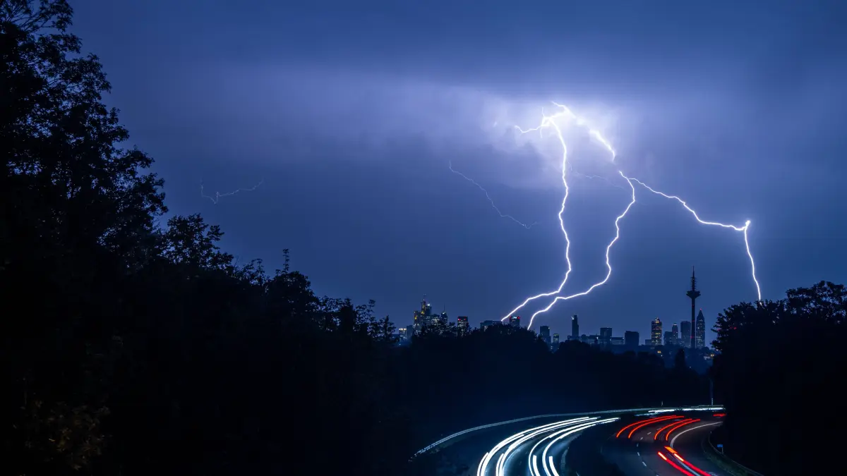 Blitze sind am Abend während eines Gewitters über der Skyline von Frankfurt am Main und der Autobahn A661 zu sehen (Archivfoto).