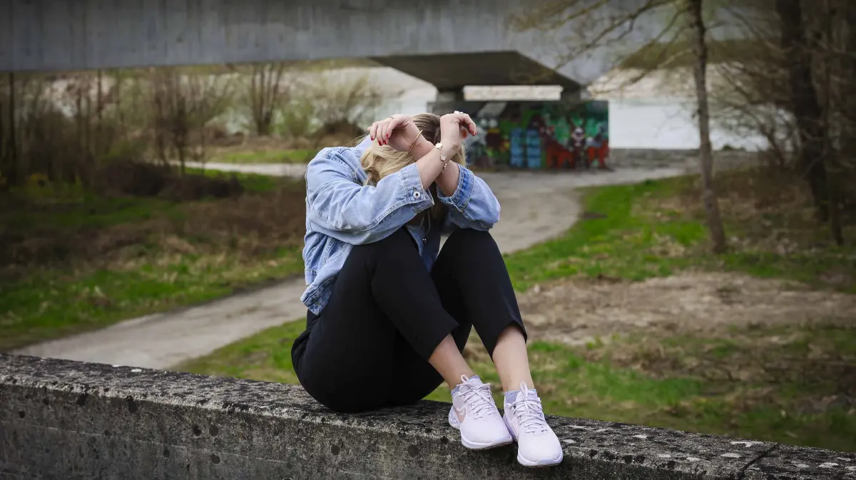 26.03.2024, Ranshofen, AUT, Unterwegs in Oberösterreich, Themenbild, Verschiedene Themenbilder, Symbolbild, im Bild Junge Frau, Traurige Frau, Mädchen, Unter Brücke, Gewalt, Frau hält schützend die Hände vors Gesicht, *** 26 03 2024, Ranshofen, AUT, On the road in Upper Austria, Theme picture, Various theme pictures, Symbolic picture, in the picture Young woman, Sad woman, Girl, Under bridge, Violence, Woman holding her hands protectively in front of her face,