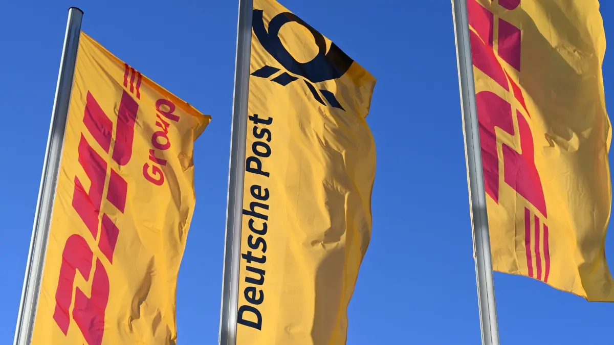 Post-Fahne mit Posthorn: ARCHIV - 13.01.2025, Nordrhein-Westfalen, Bonn: Fahnen des Logistikkonzerns DHL und seiner Brieftochter Deutsche Post (M) wehen vor der Konzernzentrale an Masten. Der Konzern hat sich von Deutsche Post AG zu DHL AG umbenannt. (zu dpa: «Bonner Logistikkonzern heißt jetzt DHL statt Deutsche Post») Foto: Wolf von Dewitz/dpa +++ dpa-Bildfunk +++