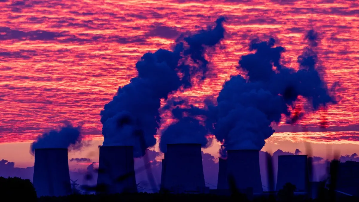 Der bevorstehende Sonnenaufgang färbt den Himmel über den Kühltürmen des Kraftwerkes Jänschwalde rot. Nach der Sabotage am Stromnetz in Südbrandenburg führt die Polizei die großräumige Durchsuchung am Ereignisort heute weiter.