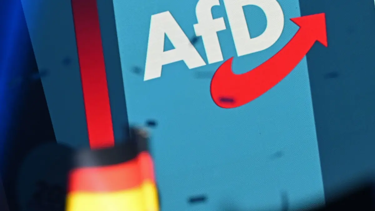 Wahlkampf Sachsen-Anhalt - AfD: 05.09.2026, Sachsen-Anhalt, Magdeburg: Ein Logo der AfD steht auf einer Wand auf einer Bühne beim AfD-Wahlkampfabschlusses im AMO Kultur- und Kongresshaus. Im Vordergrund ist eine Deutschlandfahne zu sehen. Foto: Michael Brandt/dpa +++ dpa-Bildfunk +++