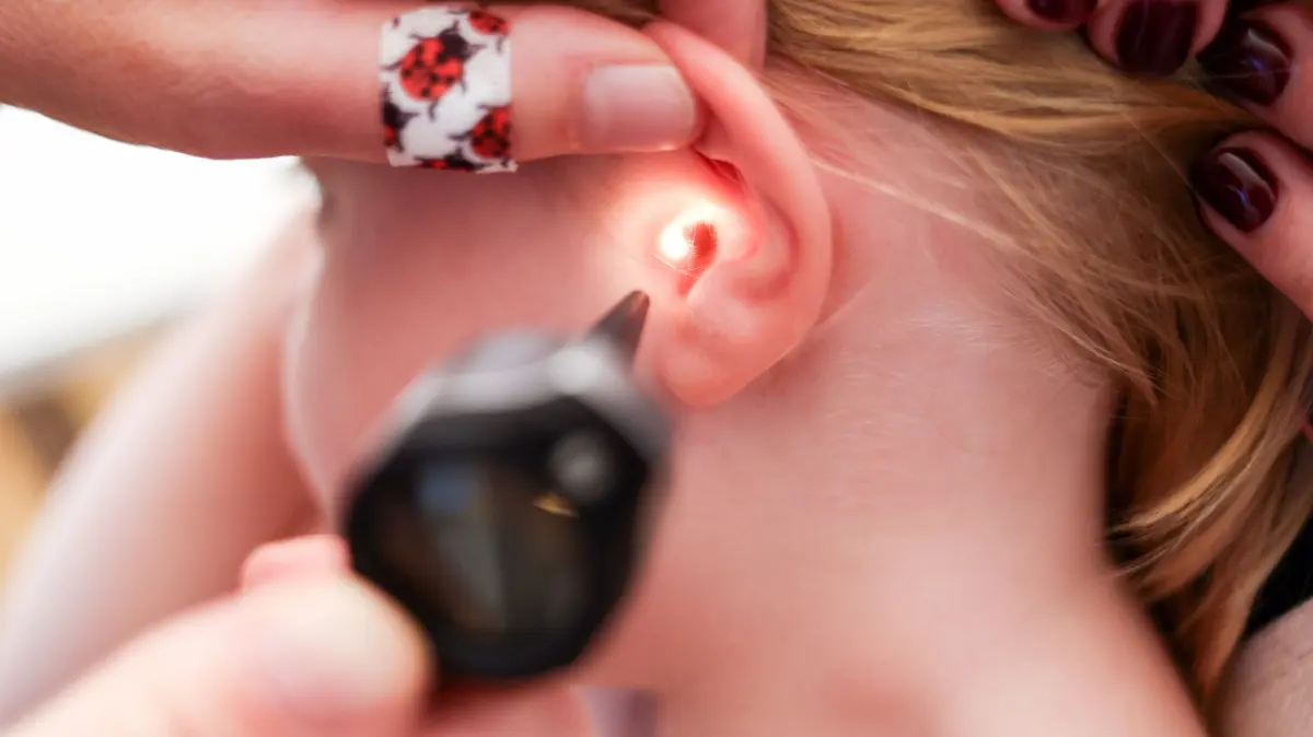 Mit einem Otoskop untersucht eine Kinderärztin das Ohr eines Mädchens bei einer Vorsorgeuntersuchung. Auf solche Termine müssen kleine Patienten künftig vermutlich länger warten.