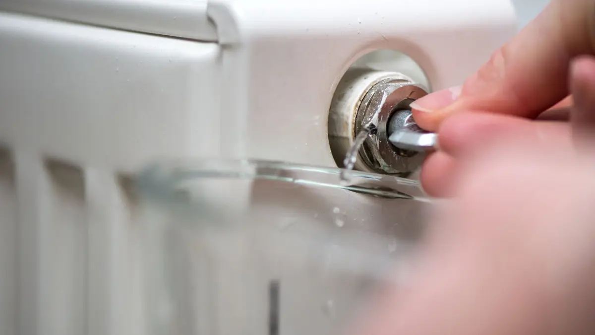 Frau entlüftet eine Heizung: ILLUSTRATION - Das Heizungsventil sollte so lange offenbleiben, bis der Heizkörper nicht mehr gluckert - und ein durchgängiger Wasserstrahl kommt. (zu dpa: «Luft raus: Auch Mieter können Ihre Heizkörper entlüften») Foto: Andrea Warnecke/dpa-mag - Honorarfrei nur für Bezieher des Dienstes dpa-Magazin +++ dpa-Magazin +++