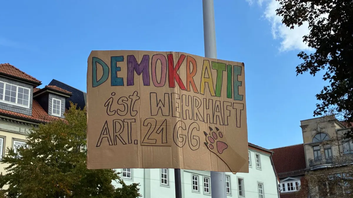 Demo für Verbotsverfahren-Prüfung von rechten Parteien: 12.09.2026, Thüringen, Erfurt: Ein Plakat mit der Aufschrift "Demokratie ist wehrhaft - Art. 21 GG" wird am Rande einer Demonstration gezeigt. Hunderte Menschen hatten sich vor der Staatskanzlei versammelt, um für ein Prüfverfahren eines Verbots von rechtsextremen Parteien zu demonstrieren. Foto: Marie Frech/dpa +++ dpa-Bildfunk +++