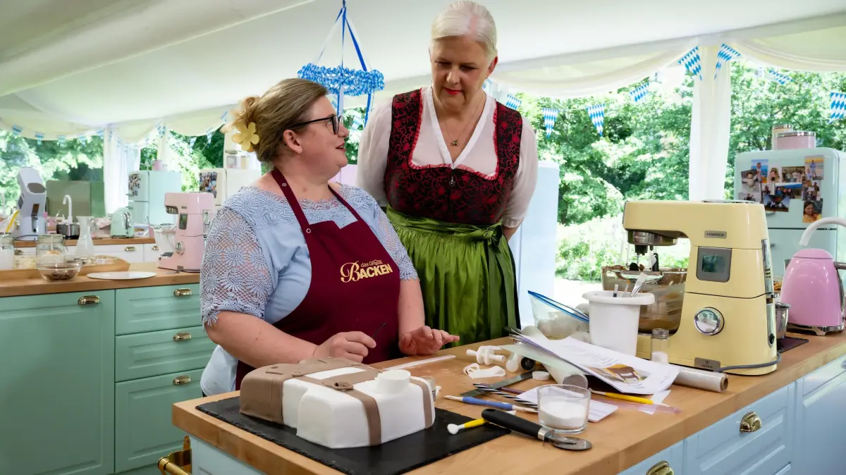 Oxana (l.) arbeitet an ihrer Wiesn-Torte im Lederhosen-Look. Jurorin Bettina Schliephake-Burchardt (r.) gibt Tipps.