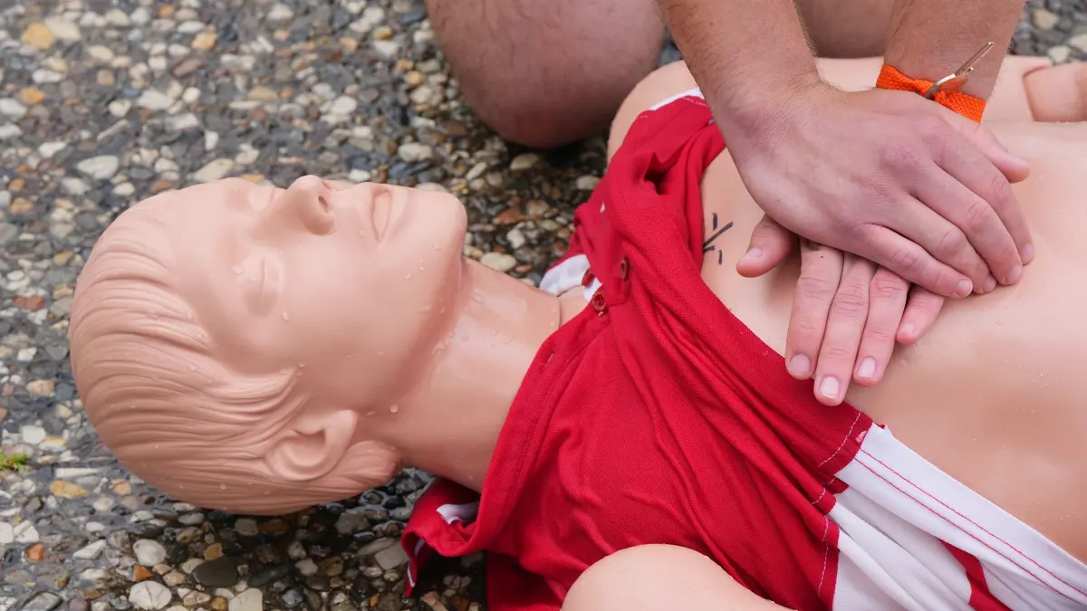 Erste-Hilfe-Kurs: ARCHIV - 14.06.2023, Berlin: Ein junger Mann zeigt im Sommerbad Humboldthain beim Vorschwimmen von potenziellen Rettungsschwimmern an einer Puppe die Methoden zur Wiederbelebung eines Verunglückten. Bei einem Herz-Kreislaufstillstand muss so früh wie möglich mit der Reanimation begonnen werden, um Leben zu retten. (zu dpa: «Wiederbelebung rettet Leben - Rekordversuch in Bielefeld») Foto: Soeren Stache/dpa +++ dpa-Bildfunk +++