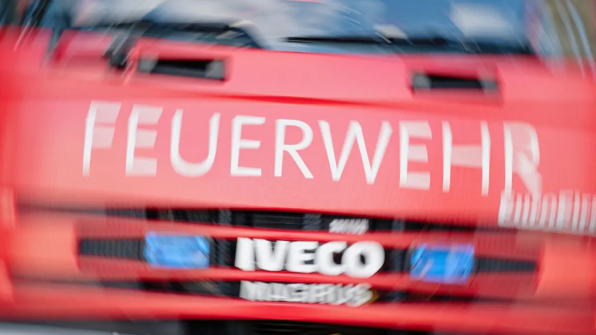 Feuerwehr: Der Schriftzug „Feuerwehr“ ist auf einem Feuerwehrfahrzeug mit aktiviertem Blaulicht angebracht. (Aufnahme mit Dreh-Effekt) (zu dpa: «Großbrand in Gutach - Bahnstrecke teils gesperrt»)