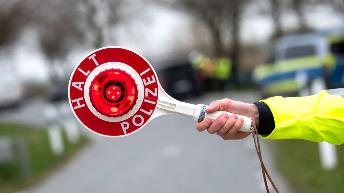 Verkehrskontrolle: Ein Beamter hält eine "Polizeikelle" mit der Aufschrift "Halt Polizei" in die Luft. (Symbolbild) (zu dpa: «Fahrer flüchtet vor Kontrolle - vier Autos im Straßengraben»)