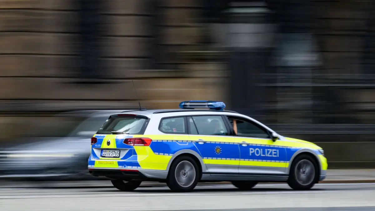 Polizei Symbolbild: ARCHIV - 23.06.2026, Sachsen, Dresden: Ein Polizeiauto fährt in Dresden über den Theaterplatz. (Aufnahme mit langer Belichtungszeit) (zu dpa: «Durchsuchungen nach bewaffneten Angriffen in Dresden») Foto: Robert Michael/dpa +++ dpa-Bildfunk +++
