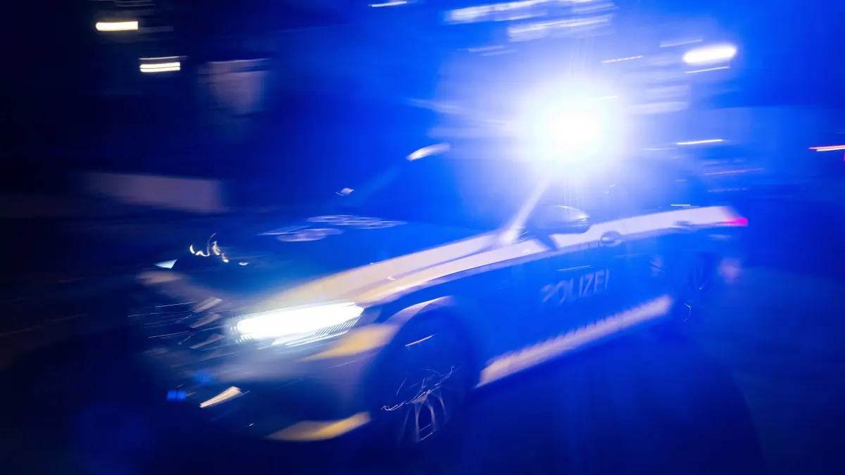 Polizei: Ein Polizeifahrzeug fährt mit Blaulicht an einem Gebäude vorbei. (zu dpa: «Junger Mann ohne Führerschein kollidiert mit Streifenwagen»)