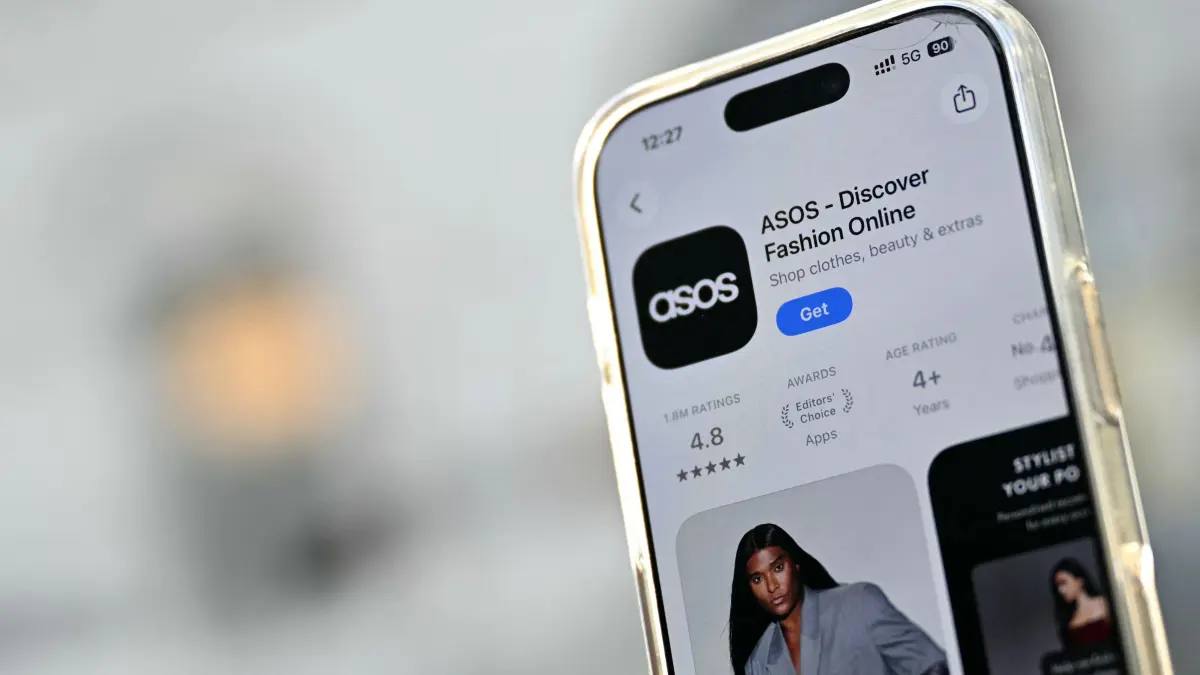 BRITAIN-CYBERCRIME-COMPUTERS-FASHION-ASOS-STOCKS: The Asos app is seen ready for download from an app store on an Apple i-phone in London on October 6, 2026. UK online fashion giant Asos saw its share price slump more than 10 percent in London trading Tuesday, October 6, after customers reportedly received a mobile notification claiming its systems had been hacked. (Photo by JUSTIN TALLIS / AFP)