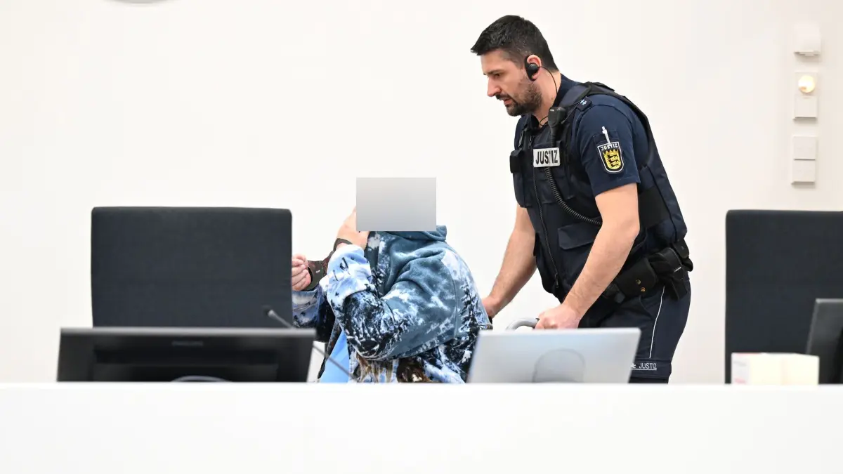Mordprozess beginnt in Ulm: 06.10.2026, Baden-Württemberg, Ulm: Ein wegen Mordes Angeklagter wird im Rollstuhl in den Gerichtssaal gefahren. Der Angeklagte soll im Februar 1985 im Raum Deggingen eine Frau getötet haben, um eine Entdeckung einer vorangegangenen Vergewaltigung und Körperverletzung der Frau zu verdecken. (zu dpa: «41 Jahre nach Tat: Angeklagter bestreitet Mordvorwurf») Foto: Felix Kästle/dpa +++ dpa-Bildfunk +++