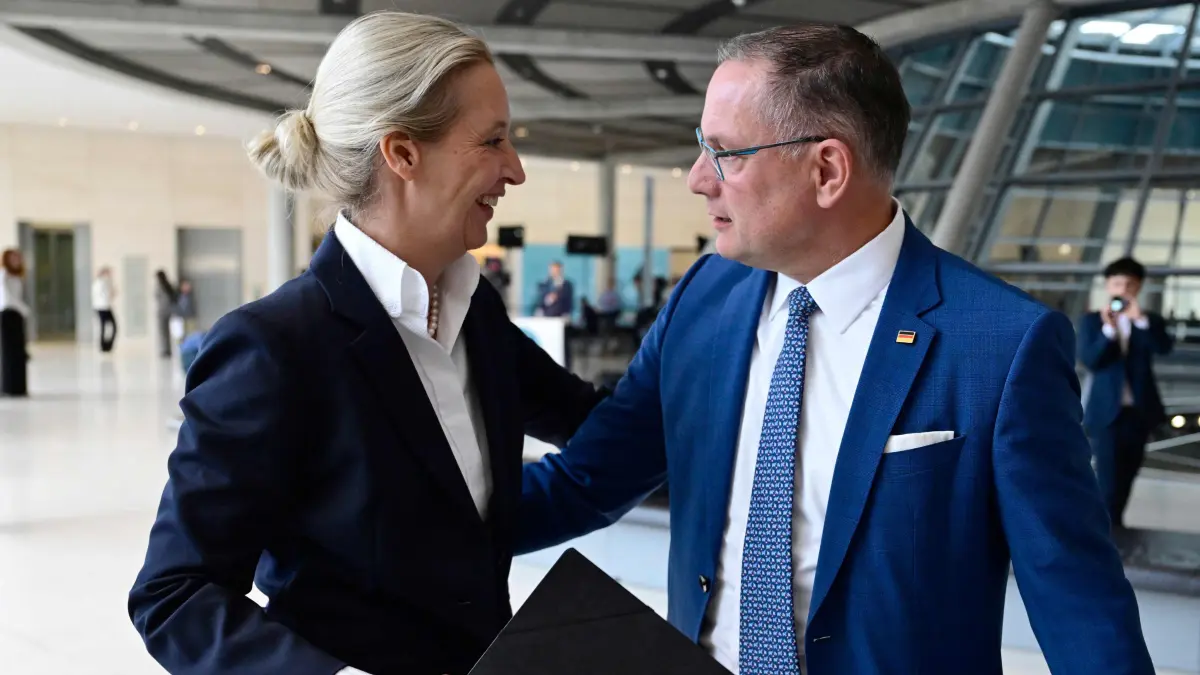 GERMANY-POLITICS-PARLIAMENT-PARTIES-AFD: The co-leaders of the far-right Alternative for Germany (AfD) party Alice Weidel (L) and Tino Chrupalla hug as they arrive to give a statement on October 6, 2026 at the Bundestag (lower house of parliament) in Berlin. (Photo by John MACDOUGALL / AFP)