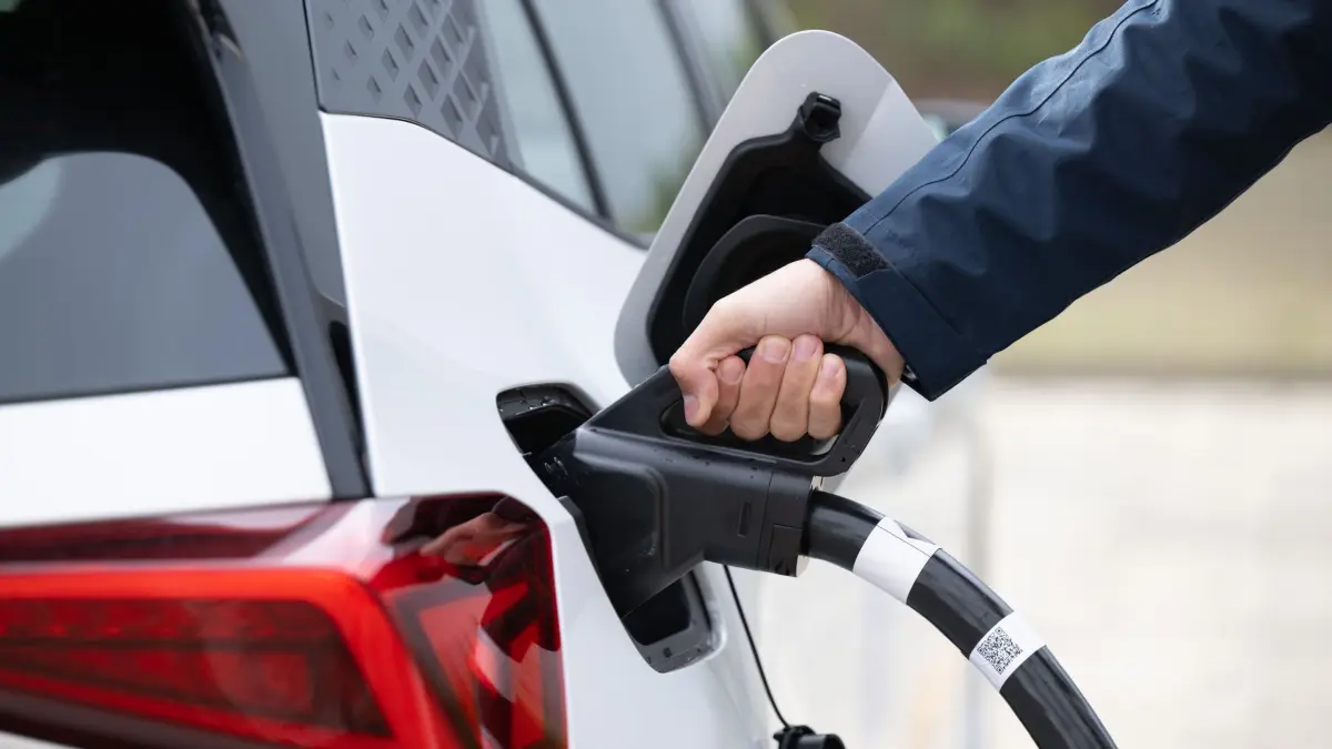 Schnellladepark für Elektromobile: ARCHIV - 22.10.2025, Sachsen, Klipphausen: Ein Mann steht auf einem Ladepark der EnBW Energie Baden-Württemberg AG und steckt ein Ladekabel in den Tankstutzen eines Elektroautos. (zu dpa: «Ladenetz für E-Autos an Autobahnparkplätzen wird ausgebaut») Foto: Sebastian Kahnert/dpa +++ dpa-Bildfunk +++
