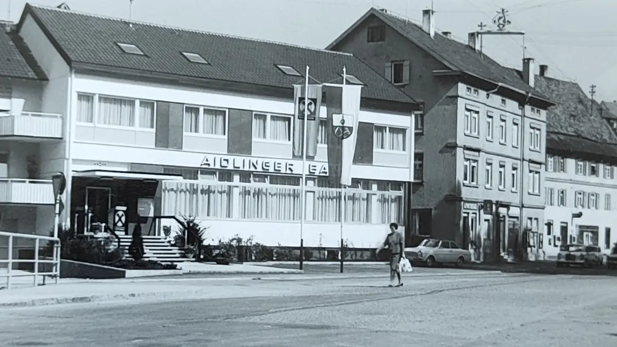 Seit 1967 hat die Aidlinger Raiba ihren Sitz an der Hauptstraße 8 in der Ortsmitte. Rechts daneben steht das alte Aidlinger Rathaus.