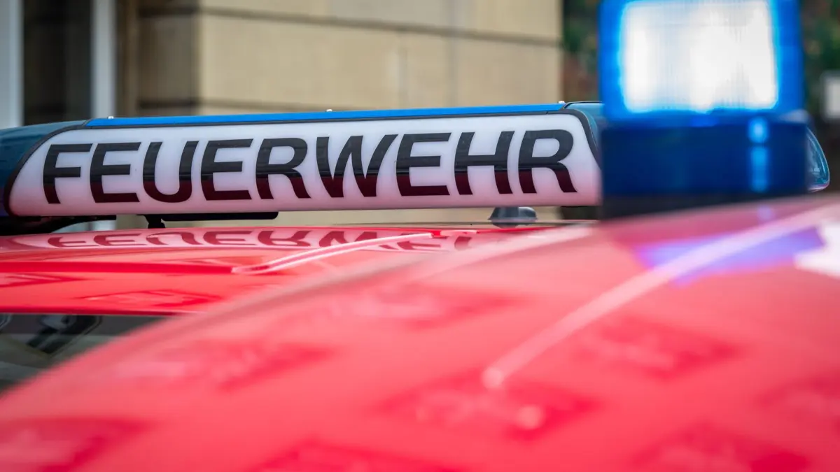 Feuerwehreinsatz in Hamburg-Farmsen: 09.10.2026, Berlin: Der Schriftzug „Feuerwehr“ ist neben einem blau leuchtenden Sondersignal auf dem Dach eines Fahrzeuges der Feuerwehr zu sehen. (zu dpa: «Gasaustritt in Farmsen: Mehrfamilienhaus evakuiert») Foto: Soeren Stache/dpa +++ dpa-Bildfunk +++