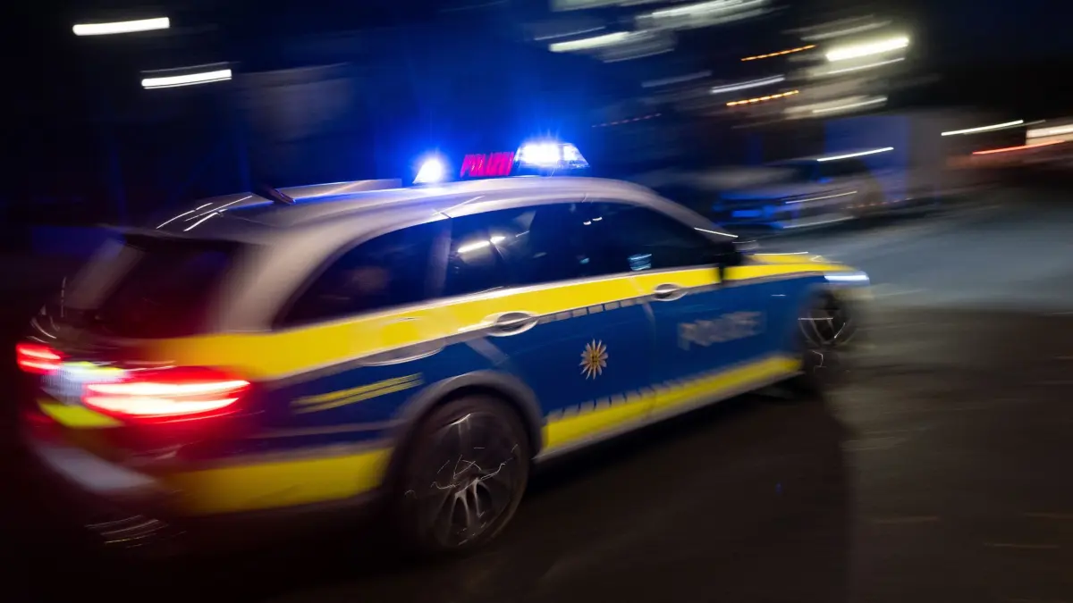 Illustration - Polizei: Ein Polizeifahrzeug fährt im Rahmen eines Fototermins mit Blaulicht an einem Gebäude vorbei (gestellte Szene, Langzeitblichtung mit Wischeffekt). (zu dpa: «Zwei Verletzte nach Schüssen in Schöneberg»)