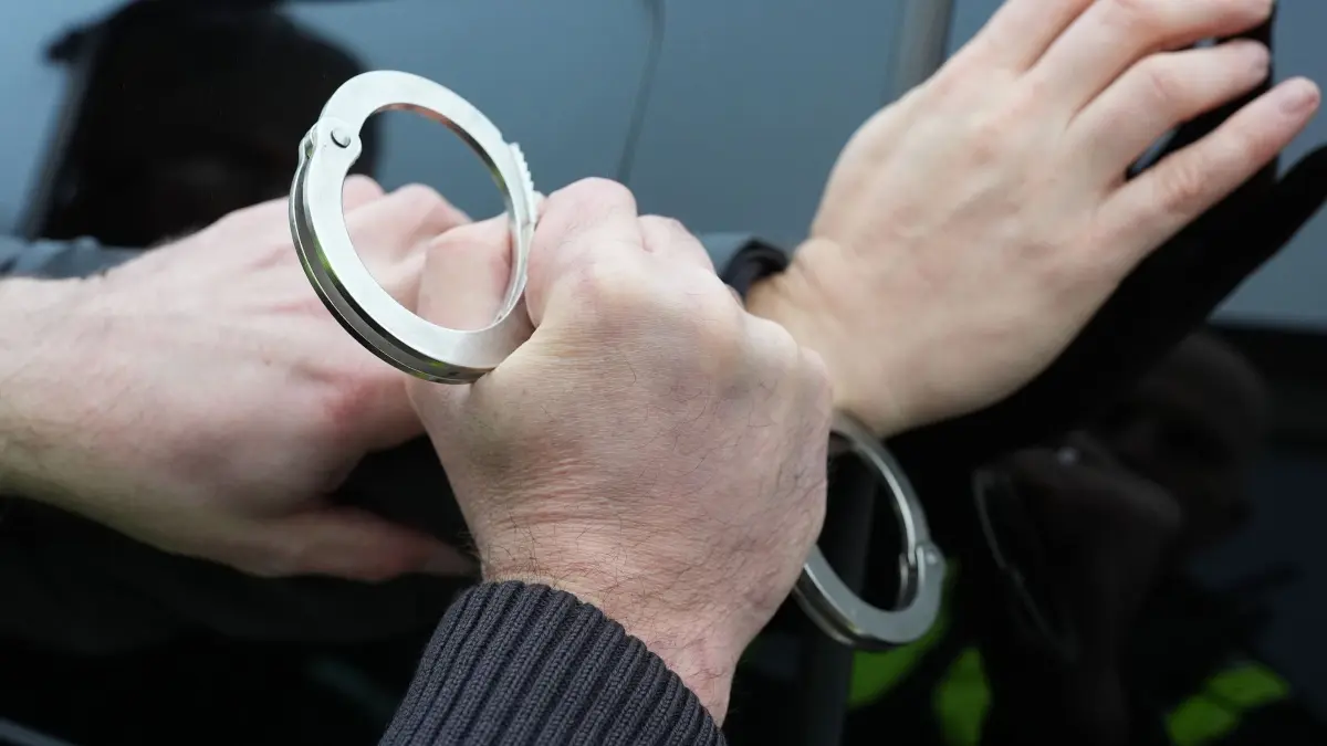 Festnahme Symbolbild: Ein Polizist legt einem Mann Handschellen an. (Symbolfoto) (zu dpa: «Waffen, Kokain und Bargeld entdeckt - zwei Männer in Haft»)