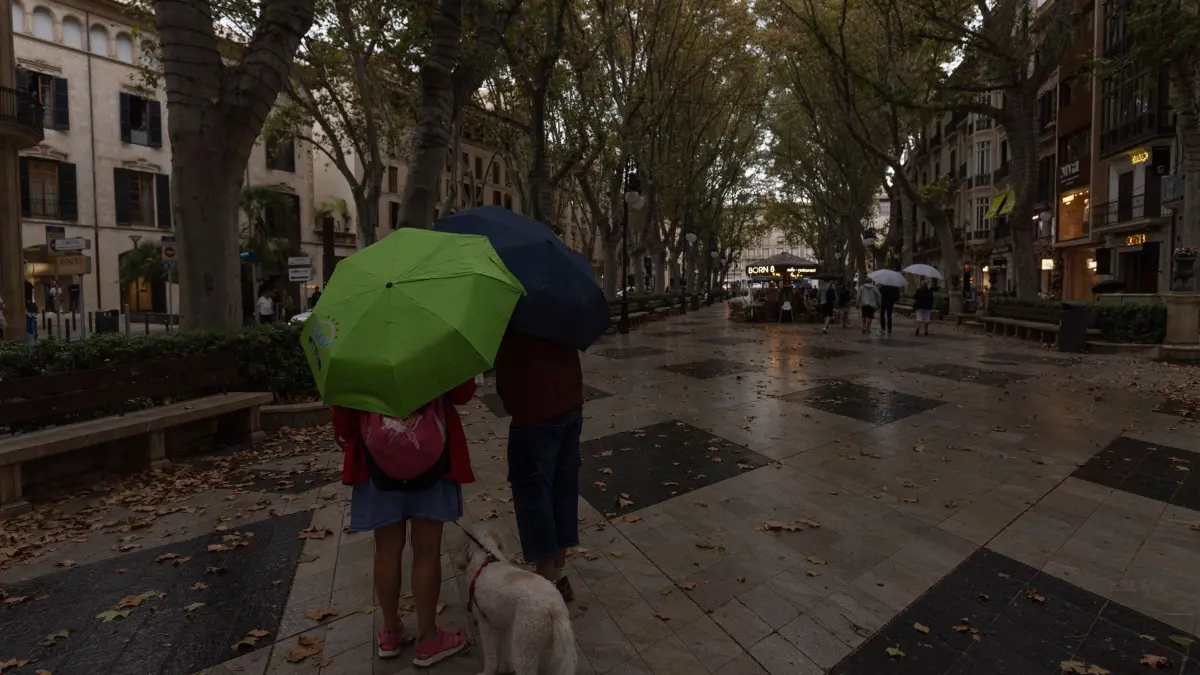 Wetter auf Mallorca: 18.10.2026, Spanien, Palma: Menschen mit Regenschirmen in der Innenstadt von Palma. Der Sturm „Adam“ zieht über die Insel hinweg, und für die Bevölkerung wurde eine rote Warnstufe ausgerufen Foto: Clara Margais/dpa +++ dpa-Bildfunk +++