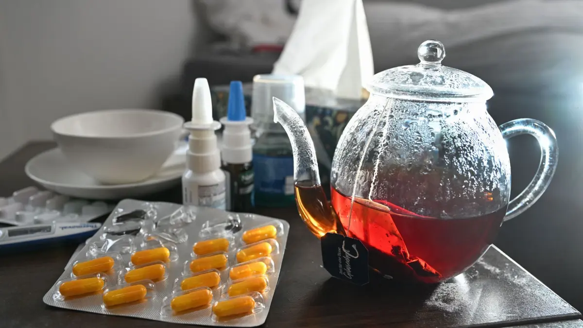 Medikamente und eine Kanne und Tasse Tee auf einem Nachttisch: Viel trinken und ausruhen: Normalerweise klingen Erkältungen innerhalb von ein bis zwei Wochen von selbst ab. (zu dpa: «Vitamin C? Warmes Bier? 8 Erkältungstipps im Check»)