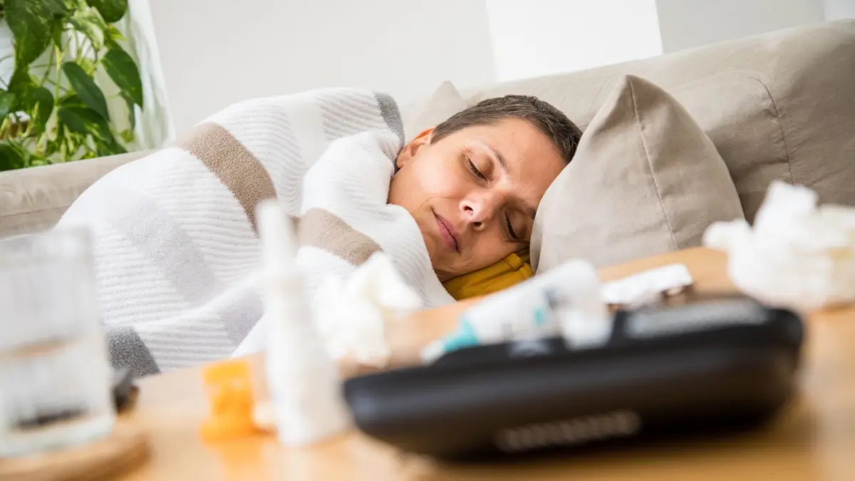 Eine Frau liegt krank auf einem Sofa: Schmerzmittel und Nasenspray lindern Symptome einer Erkältung - schneller gesund wird man dadurch aber in der Regel nicht. (zu dpa: «Vitamin C? Warmes Bier? 8 Erkältungstipps im Check»)