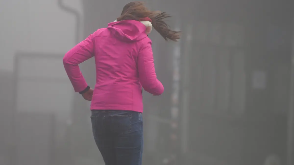 Frau kämpft auf dem Großen Feldberg im Taunus gegen Wind an: Wer im Freien von einem Sturm oder Gewitter überrascht wird, sollte schnell geeigneten Schutz suchen oder eine sichere Haltung einnehmen. (zu dpa: «Plötzlich im Sturm: Notfalltipps für Fußgänger»)