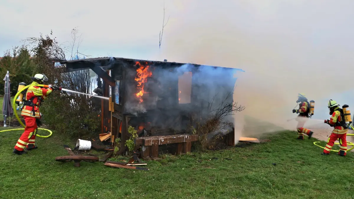 24.10.2026: Mit dem Alarmstichwort 1bi wurde die Freiwillige Feuerwehr Leonberg am Samstagmorgen (24.10.2026) um kurz nach 8 Uhr alarmiert. Der Einsatzort befand sich laut Leitstelle in der Verlängerung der Jahnstraße in Richtung Felder. Die Anfahrt konnte auf Sicht erfolgen, eine weithin sichtbare Rauchwolke wies den Einsatzkräften den Weg. Beim Eintreffen der ersten Einheiten brannte ein größeres Gartenhaus lichterloh in voller Ausdehnung. Umgehend wurden zwei C-Rohre unter Atemschutz vorgenommen, parallel dazu vom nächsten Hydranten aus eine Wasserversorgung aufgebaut. Da absehbar war, dass eine größere Anzahl an Atemschutzgeräten benötigt werden würde, forderte der Einsatzleiter die beiden Abrollbehälter Atemschutz und Hygiene nach. Nachlöscharbeiten zogen sich noch bis nach 10 Uhr hin. Die Leonberger Feuerwehr war mit dem Kommandowagen, dem Einsatzleitwagen, zwei Hilfeleistungslöschfahrzeugen, dem Großtanklöschfahrzeug, einem Gerätewagen-Transport und den beiden Wechselladerfahrzeugen vor Ort.
Foto: KS-Images.de / Andreas Rometsch