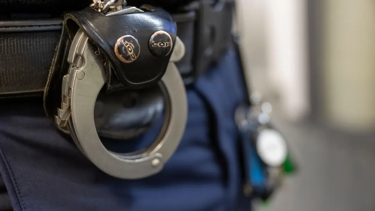 Polizei: Eine Handschelle hängt am Gürtel eines Polizisten. (zu dpa: «17-Jähriger hat keine Fahrkarte und schlägt Kontrolleur»)