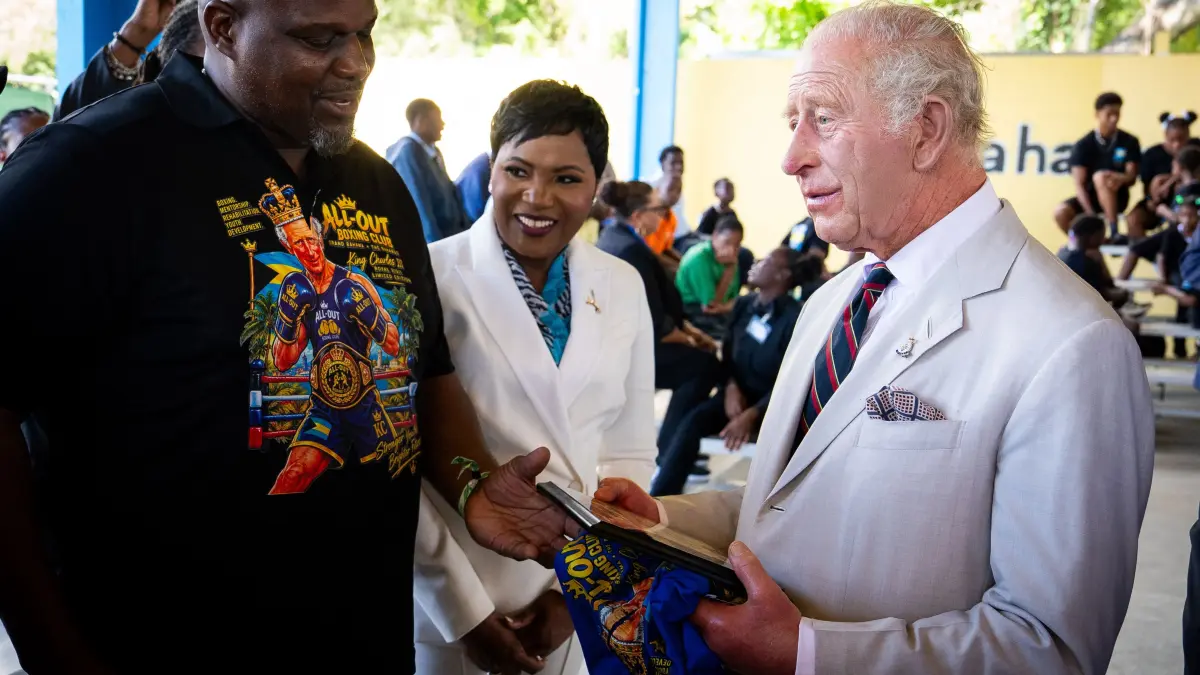 BAHAMAS-BRITAIN-ROYALS: Britain's King Charles III (R) is presented with a t-shirt, featuring an illustration depicting him as a boxer, by boxing coach Jermaine Gibson during his visit to the Bahamas Boxing Academy in Nassau, The Bahamas, on October 28, 2026. King Charles III's Autumn Tour includes visits to The Bahamas, Guyana and Antigua and Barbuda. (Photo by Aaron Chown / POOL / AFP)
