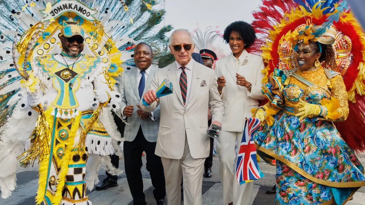 König Charles III. auf den Bahamas: dpatopbilder - 28.10.2026, Bahamas, Nassau: König Charles III. schüttelt traditionelle Kuhglocken, während er zusammen mit Junkanoo-Tänzern an einem Kulturfestival auf dem Rawson Square in Nassau, Bahamas, vorbeizieht, flankiert von Jomo Campbell, Minister für Landwirtschaft und Meeresressourcen (l), und Leslia Brice, Ministerin für Kultur, Kunst und Kulturerbe (r). Foto: Tim Aylen/AP/dpa +++ dpa-Bildfunk +++