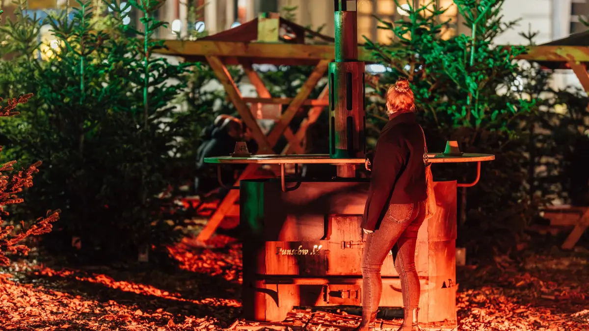 Der Punschwald eröffnet am Berliner Platz: 30.10.2026, Stuttgart: Eine junge Frau genießt die Eröffnung des Punschwalds am Berliner Platz an einem warmen Ofen. Erstmalig findet der Punschwald nicht mehr im ehemaligen W&W Areal am Feuersee, sondern am Berliner Platz statt. Foto: Lichtgut/Christoph Schmidt